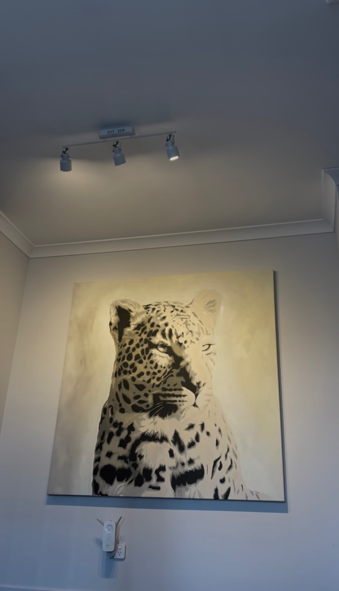 Stencil leopard painting hung under gallery spotlights
