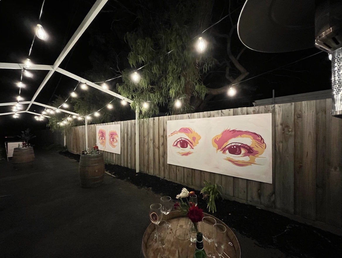 Pair of large eye paintings displayed outdoors at night