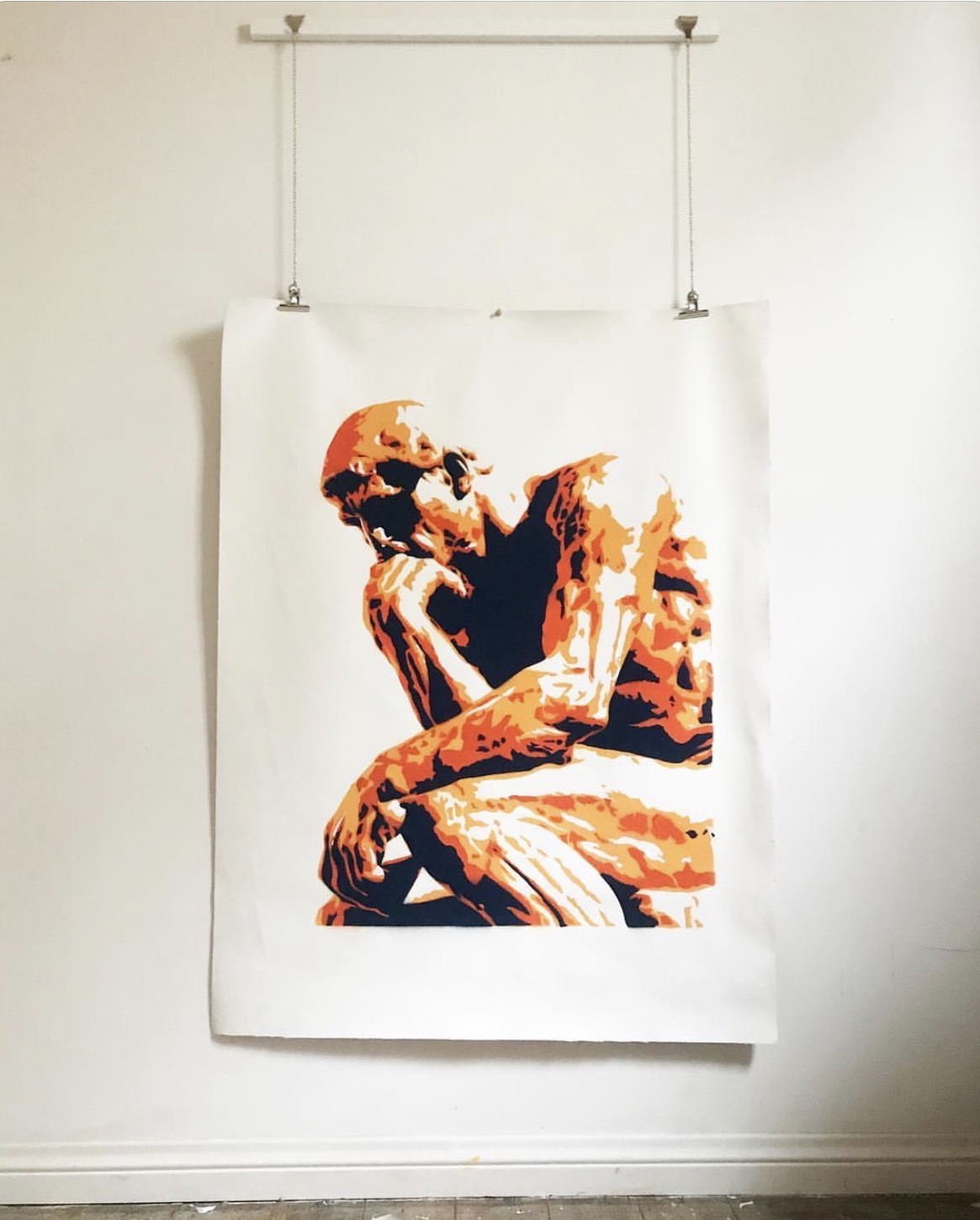 Orange stencil print of The Thinker on paper